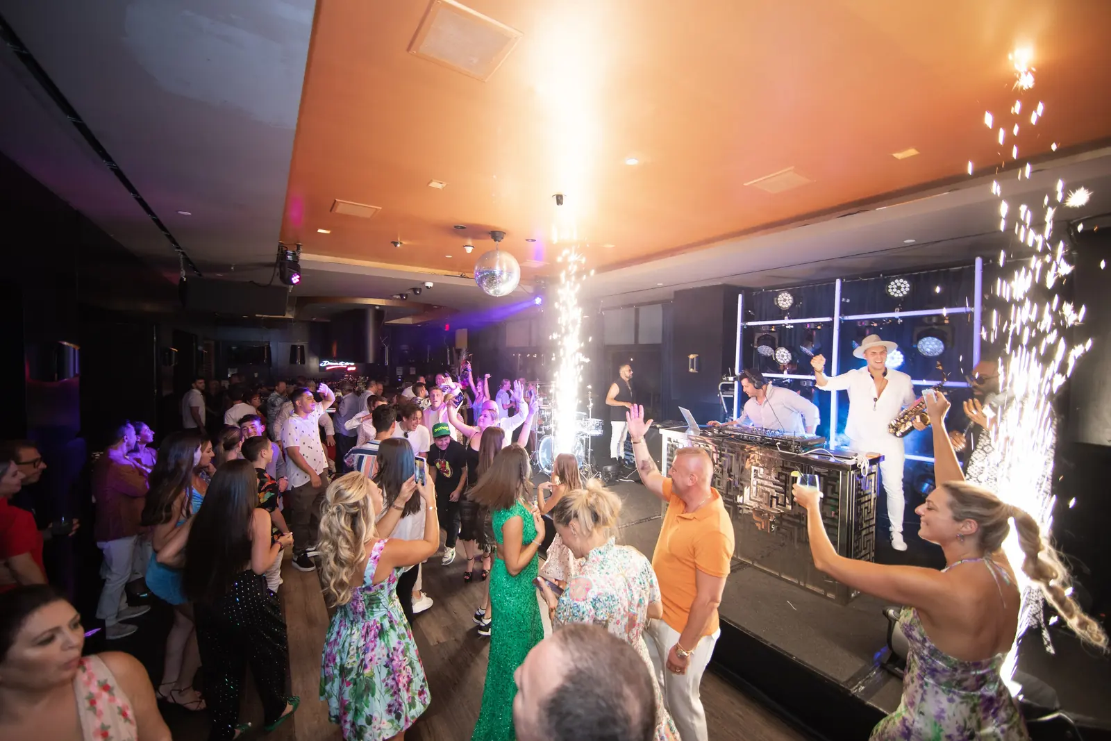 Packed dance floor with cold spark fountains at an evening event