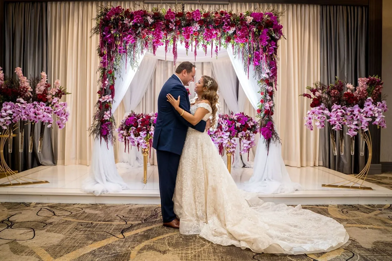 Bride and groom under a floral arch at a Los Angeles wedding